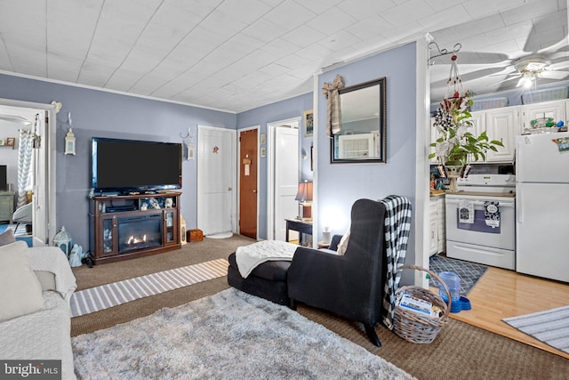 living room with ceiling fan, ornamental molding, and carpet