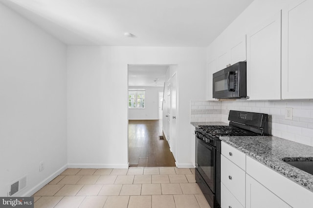 kitchen featuring light stone counters, white cabinets, backsplash, black appliances, and light hardwood / wood-style flooring