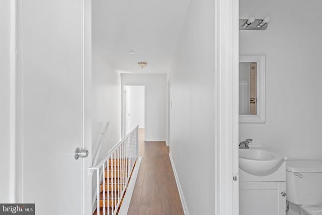 corridor with hardwood / wood-style flooring and sink