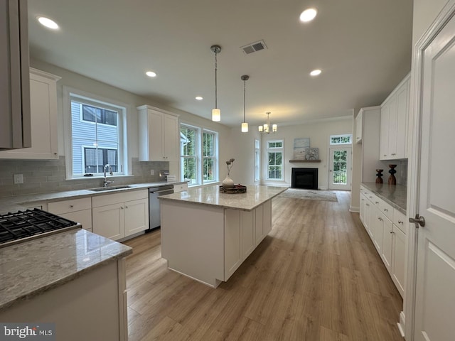 kitchen with light stone counters, sink, white cabinetry, and a kitchen island