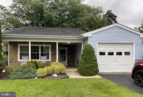 view of front of home featuring covered porch, a front yard, and a garage