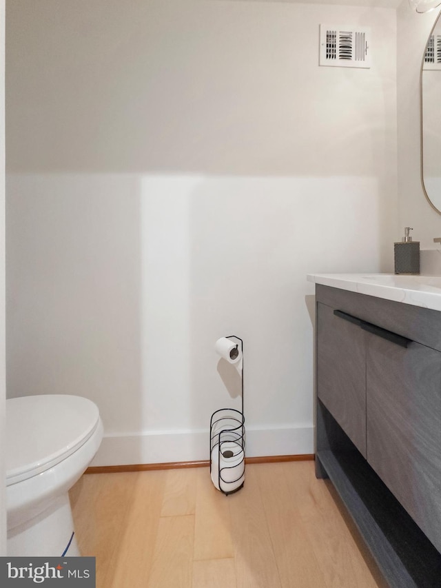 bathroom with toilet, vanity, and wood-type flooring