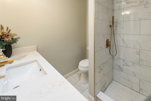 bathroom featuring toilet, tiled shower, and vanity