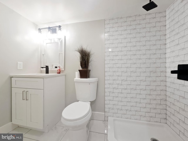 bathroom featuring toilet, tiled shower, and vanity