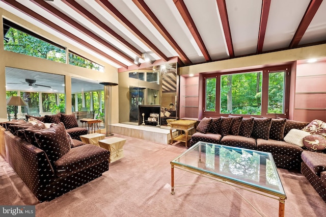 carpeted living room featuring a premium fireplace, beamed ceiling, plenty of natural light, and ceiling fan