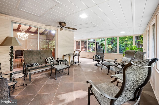 sunroom featuring ceiling fan with notable chandelier