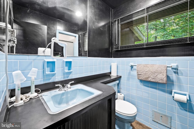 bathroom with vanity, tile walls, and toilet