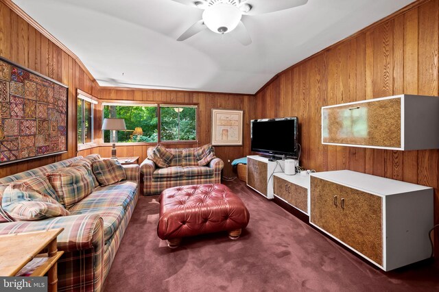 living room featuring lofted ceiling, dark colored carpet, ceiling fan, and wood walls