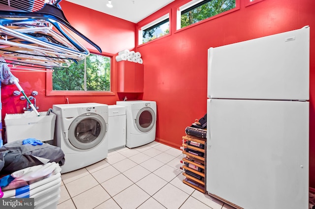 washroom with washing machine and clothes dryer, light tile patterned floors, and sink