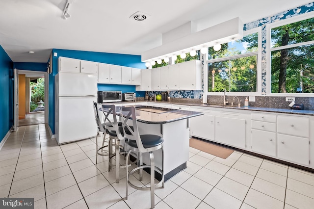 kitchen with white cabinets, white refrigerator, and a wealth of natural light