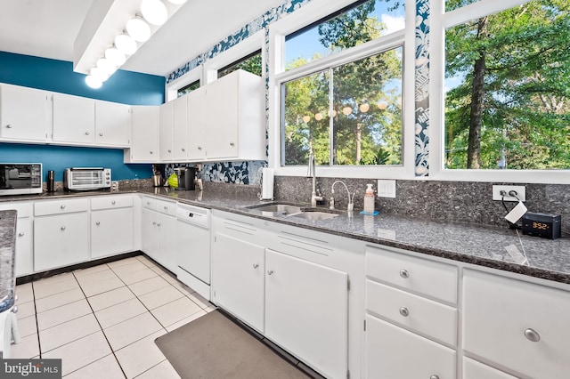 kitchen featuring light tile patterned flooring, sink, white appliances, white cabinetry, and dark stone counters