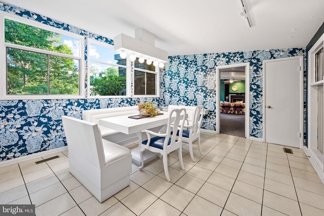 tiled dining space featuring vaulted ceiling and track lighting