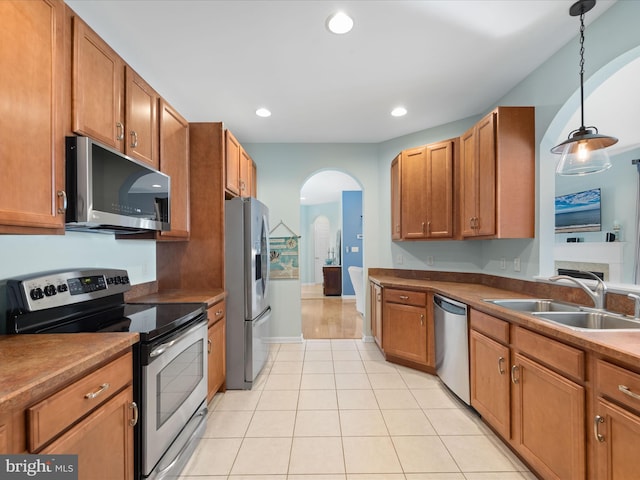 kitchen with sink, light tile patterned floors, stainless steel appliances, and decorative light fixtures