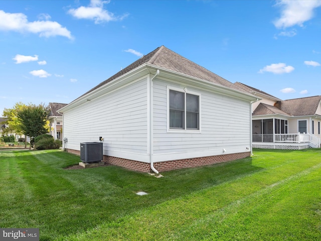 view of side of home featuring cooling unit, a sunroom, and a lawn