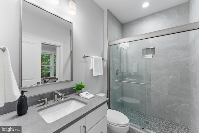 bathroom with vanity, toilet, and a shower with door