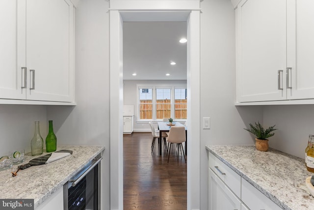 kitchen with white cabinetry, dark wood-type flooring, wine cooler, and light stone counters