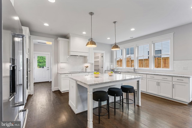 kitchen featuring a kitchen island, decorative light fixtures, white cabinetry, dark hardwood / wood-style flooring, and decorative backsplash