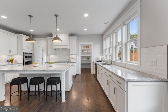 kitchen with pendant lighting, dark hardwood / wood-style floors, white cabinets, and a kitchen island