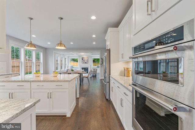 kitchen featuring appliances with stainless steel finishes, white cabinetry, dark hardwood / wood-style flooring, and pendant lighting