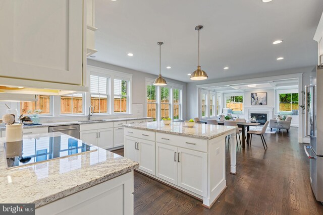 kitchen featuring white cabinets, light stone counters, a center island, and a healthy amount of sunlight