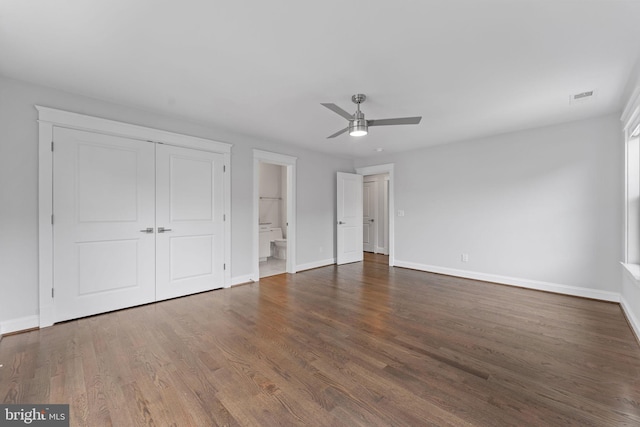 unfurnished bedroom featuring ceiling fan, a closet, ensuite bath, and dark wood-type flooring