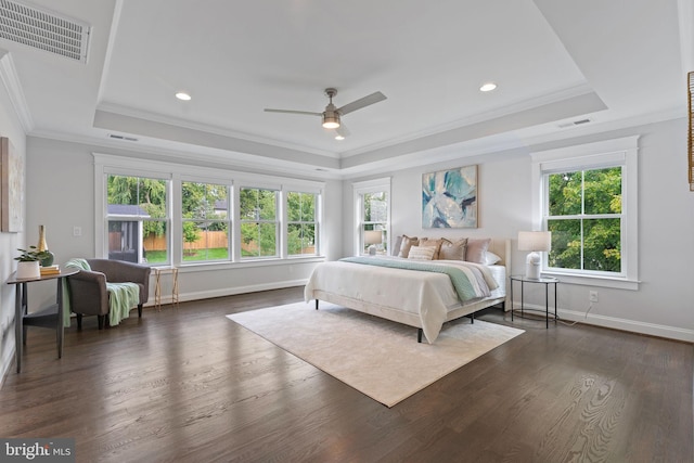 bedroom with a tray ceiling, dark hardwood / wood-style flooring, and multiple windows