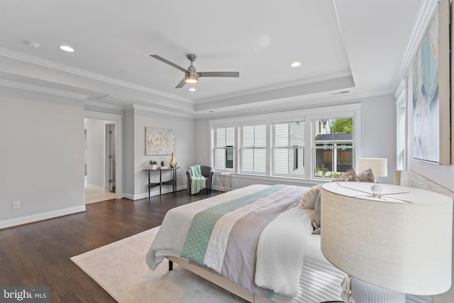 bedroom with ceiling fan, a tray ceiling, crown molding, and dark wood-type flooring