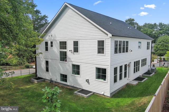 rear view of house featuring a lawn and cooling unit