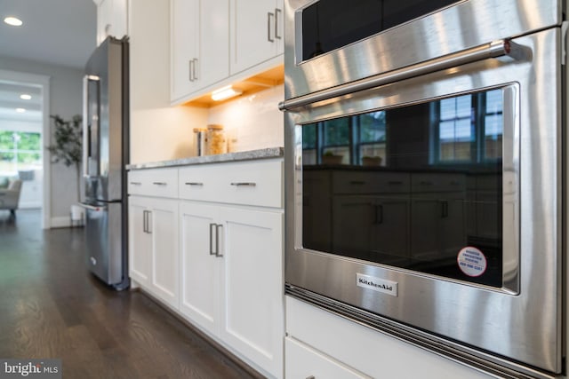 kitchen with appliances with stainless steel finishes, dark hardwood / wood-style floors, and white cabinets