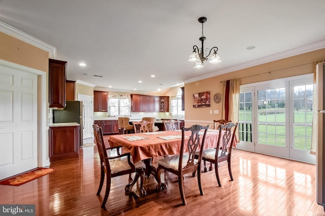 dining space with crown molding, hardwood / wood-style flooring, and a notable chandelier