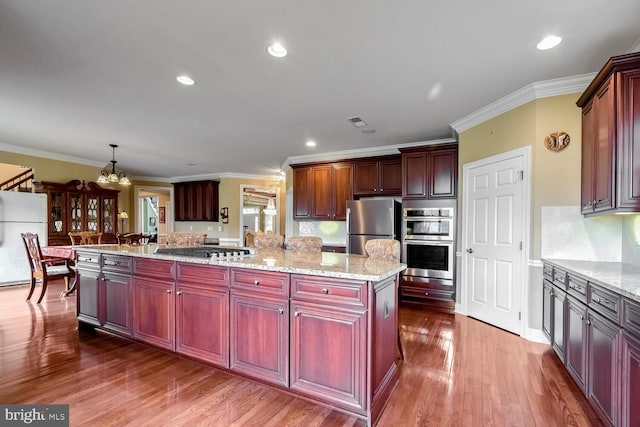 kitchen featuring a center island, crown molding, appliances with stainless steel finishes, decorative light fixtures, and a chandelier