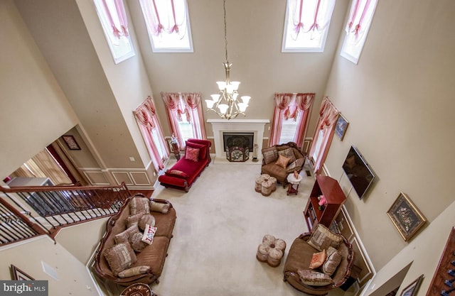 living room featuring carpet flooring, a towering ceiling, and a chandelier