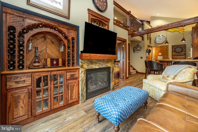 living room with a premium fireplace, high vaulted ceiling, and wood-type flooring