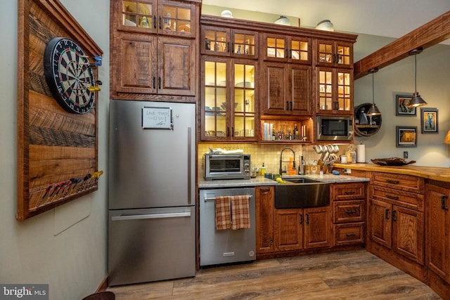 kitchen with decorative backsplash, hanging light fixtures, dark hardwood / wood-style flooring, sink, and stainless steel appliances