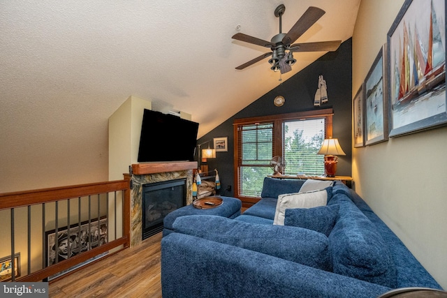 living room featuring a textured ceiling, a high end fireplace, ceiling fan, lofted ceiling, and light hardwood / wood-style flooring