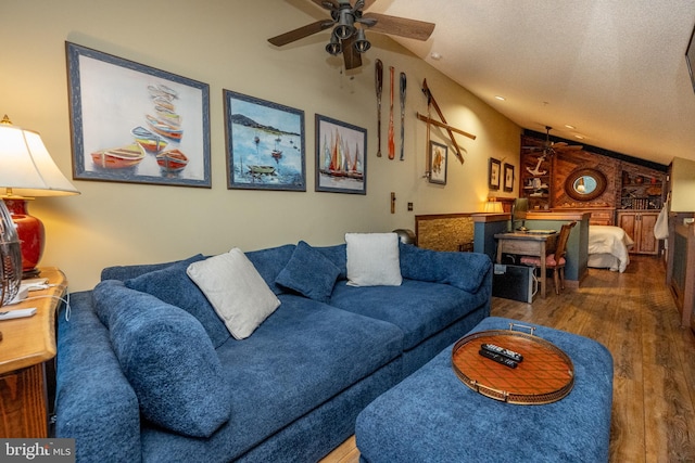 living room with a textured ceiling, ceiling fan, lofted ceiling, wooden walls, and dark wood-type flooring