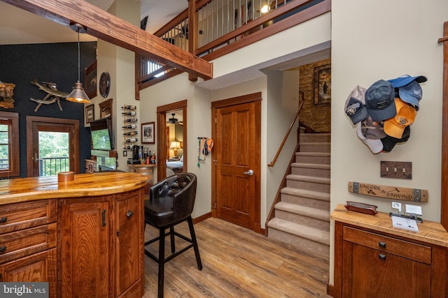 kitchen with a kitchen bar, decorative light fixtures, light wood-type flooring, high vaulted ceiling, and ceiling fan