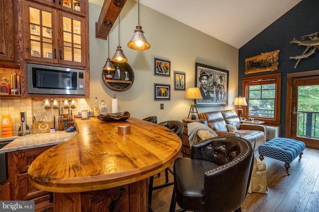 bar with stainless steel microwave, dark wood-type flooring, backsplash, light stone countertops, and high vaulted ceiling