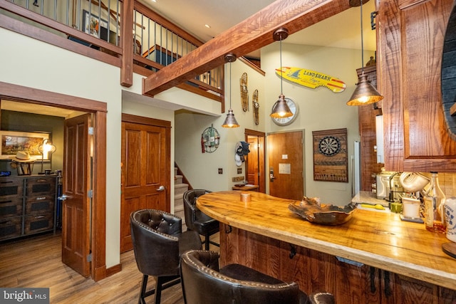 bar with butcher block counters, hanging light fixtures, and light wood-type flooring