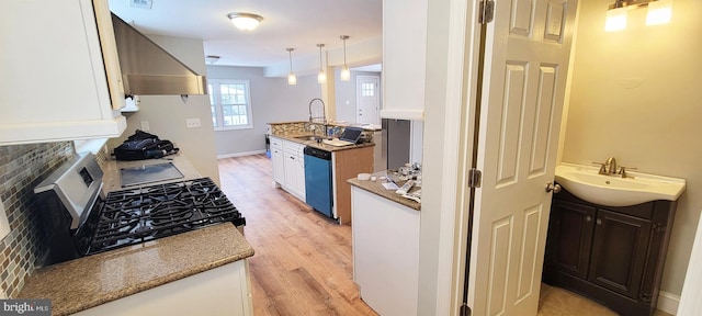 kitchen with wall chimney range hood, sink, hanging light fixtures, appliances with stainless steel finishes, and white cabinetry