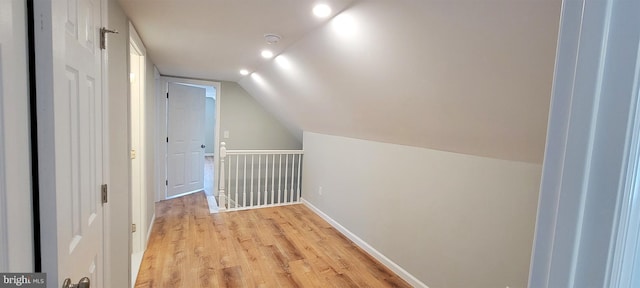 additional living space with light wood-type flooring and vaulted ceiling