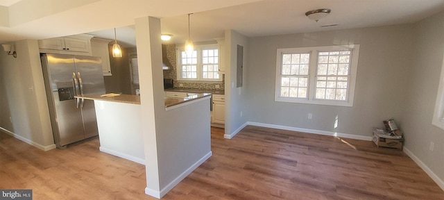 kitchen with decorative backsplash, stainless steel fridge with ice dispenser, hardwood / wood-style floors, and pendant lighting