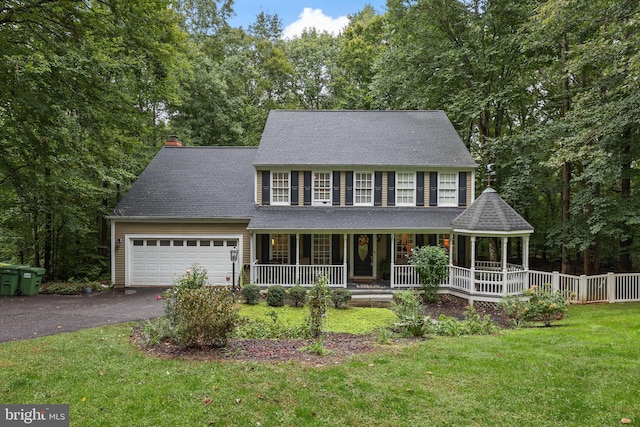 colonial-style house featuring a front yard, a garage, and covered porch