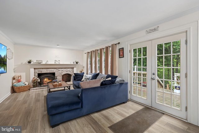 living room with a brick fireplace, light hardwood / wood-style floors, and french doors