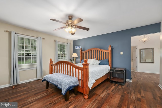 bedroom featuring ceiling fan with notable chandelier, multiple windows, and dark wood-type flooring