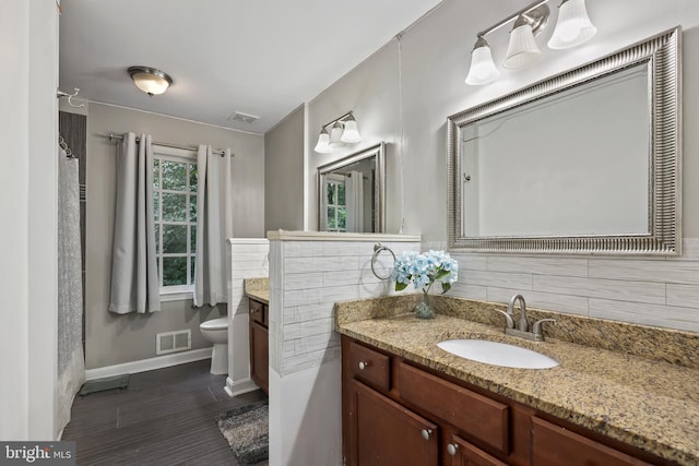 bathroom with backsplash, vanity, and toilet