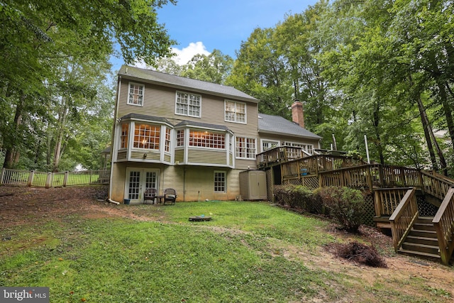 rear view of house featuring french doors, a fire pit, a deck, and a yard