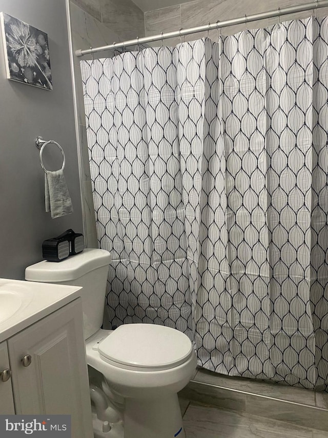 bathroom with vanity, toilet, hardwood / wood-style flooring, and walk in shower