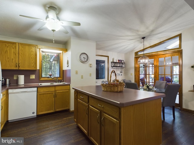 kitchen featuring white dishwasher, sink, dark hardwood / wood-style floors, a kitchen island, and hanging light fixtures