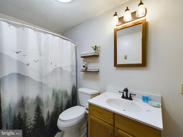 bathroom with vanity, toilet, and a textured ceiling